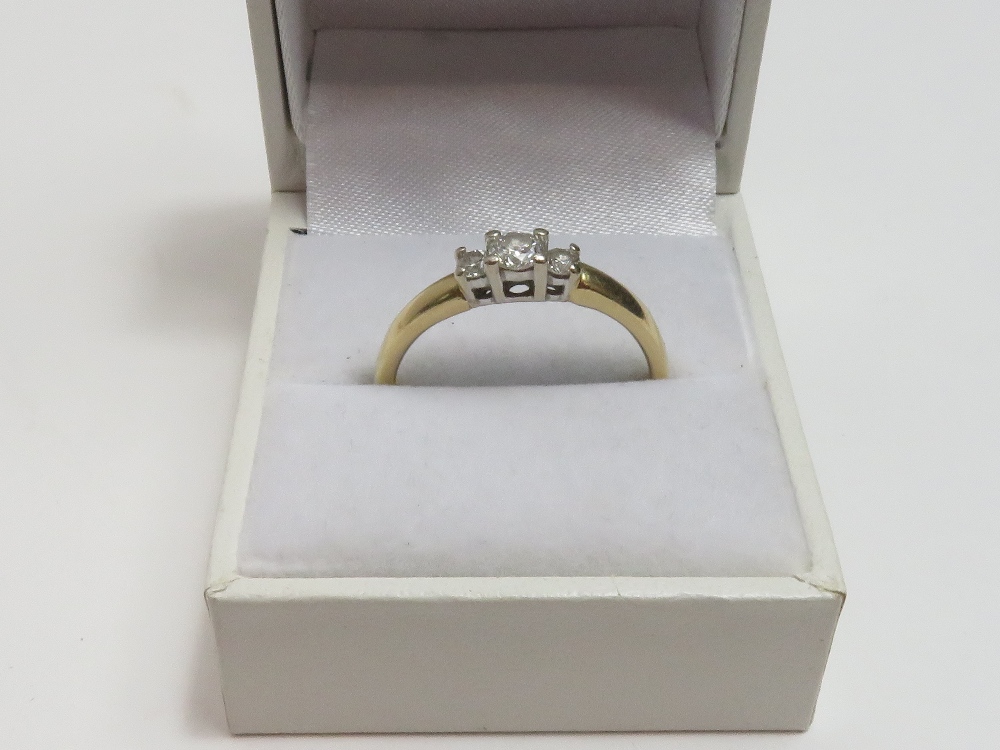 A 14k three stone diamond ring, the central stone flanked by smaller stones