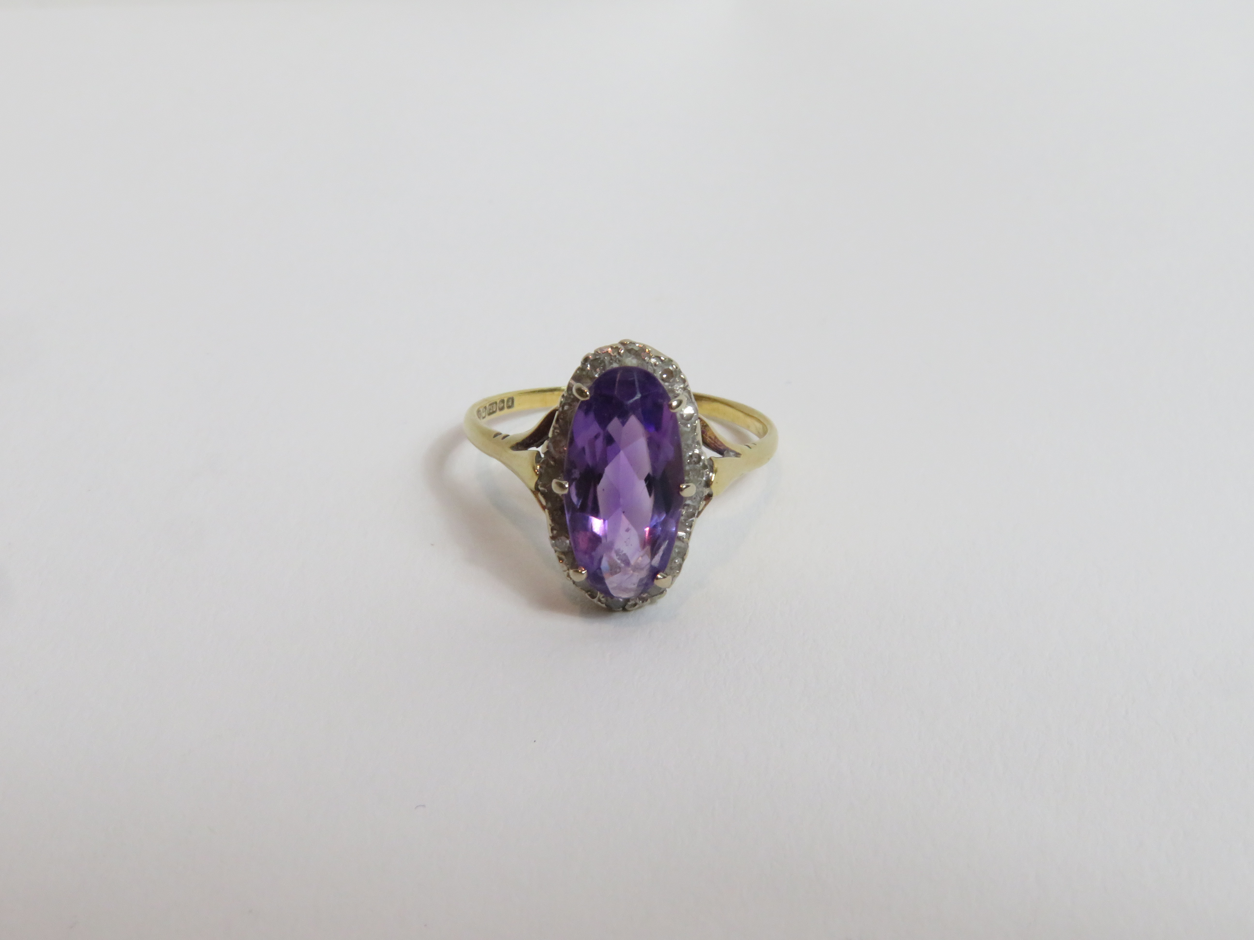 An amethyst and diamond 18 carat gold cluster ring, Birmingham 1975, the long oval cut stone