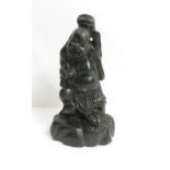 A Japanese wood carving of man holding a fish above his head, standing on rocky base with a toad