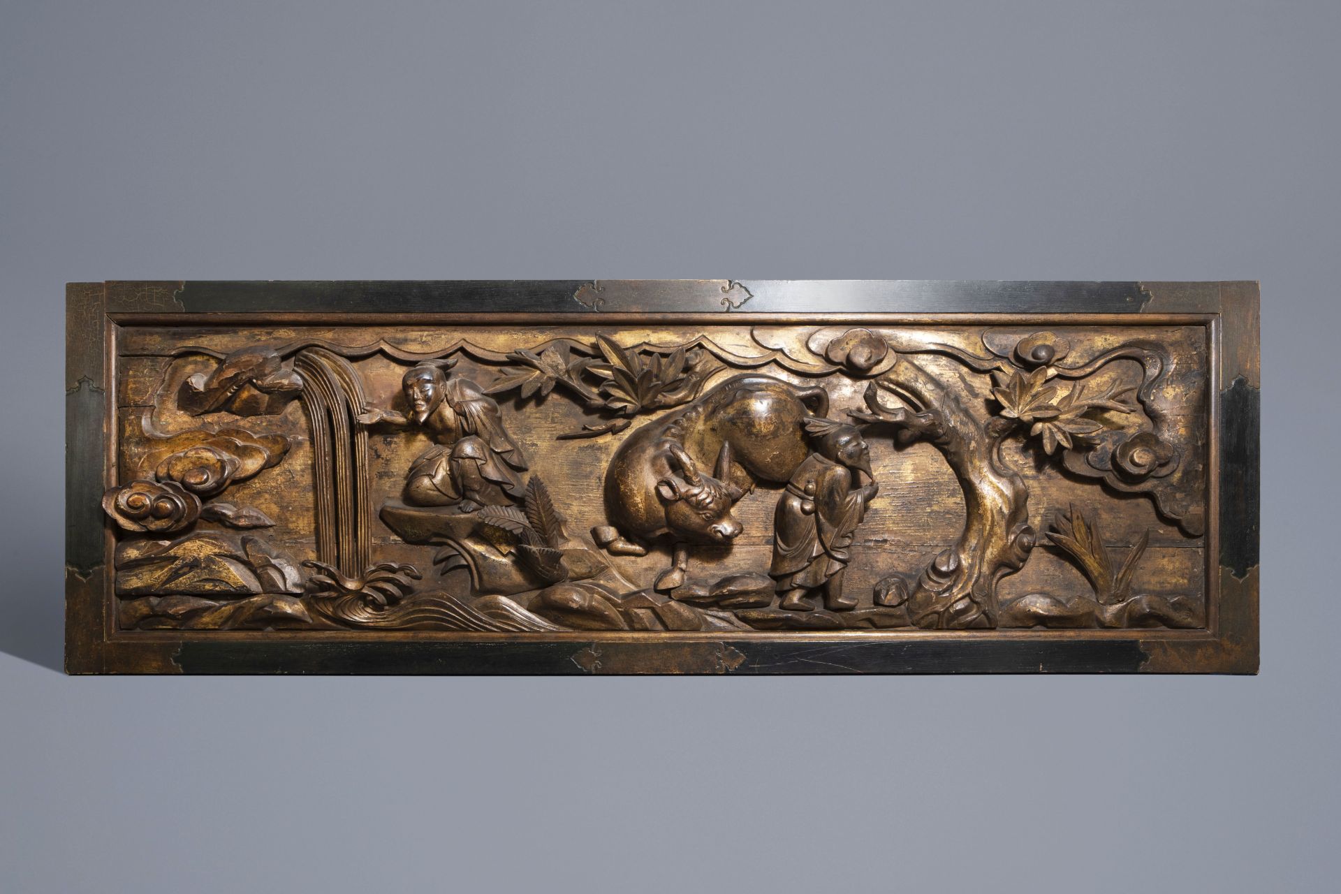 A large Chinese partly gilt carved wooden panel with a water buffalo, 19th C.