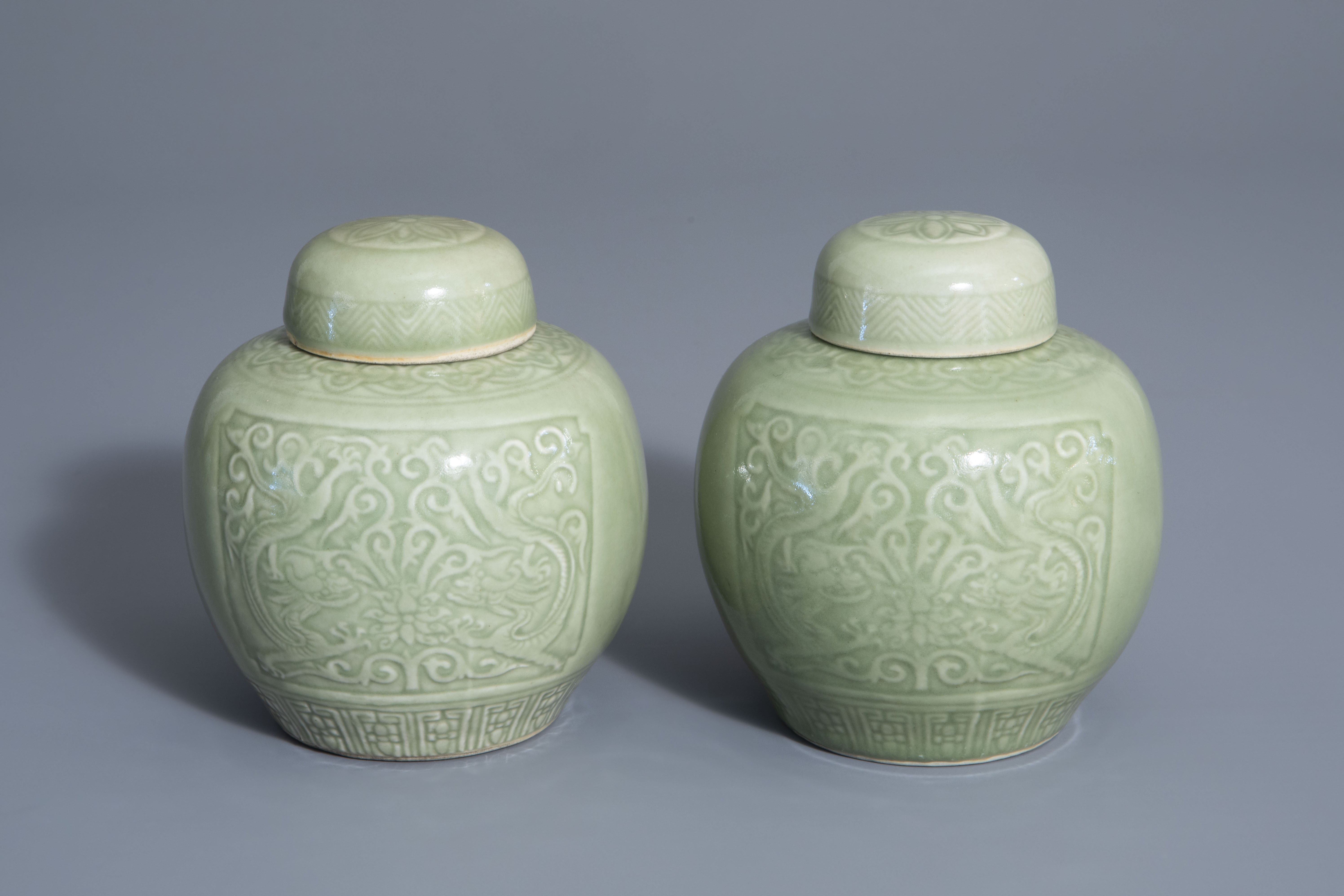 A pair of Chinese celadon jars and covers with underglaze dragon design, 19th/20th C.