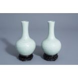 A pair of Chinese monochrome celadon bottle vases with incised phoenix medallions, Yongzheng mark, 1
