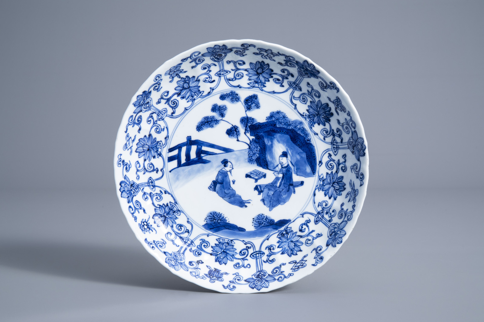 A Chinese blue and white plate with a tea ceremony and floral design, Kangxi mark and of the period