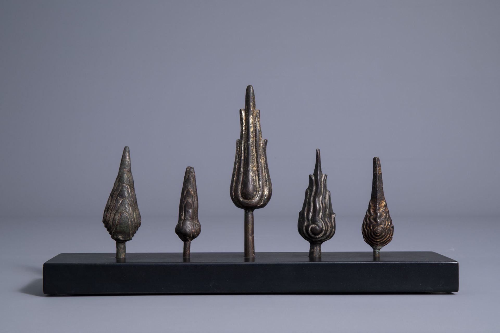 Five patinated and gilt bronze ushnishas on a wooden stand, Thailand/Cambodia, 19th/20th C. - Image 2 of 7