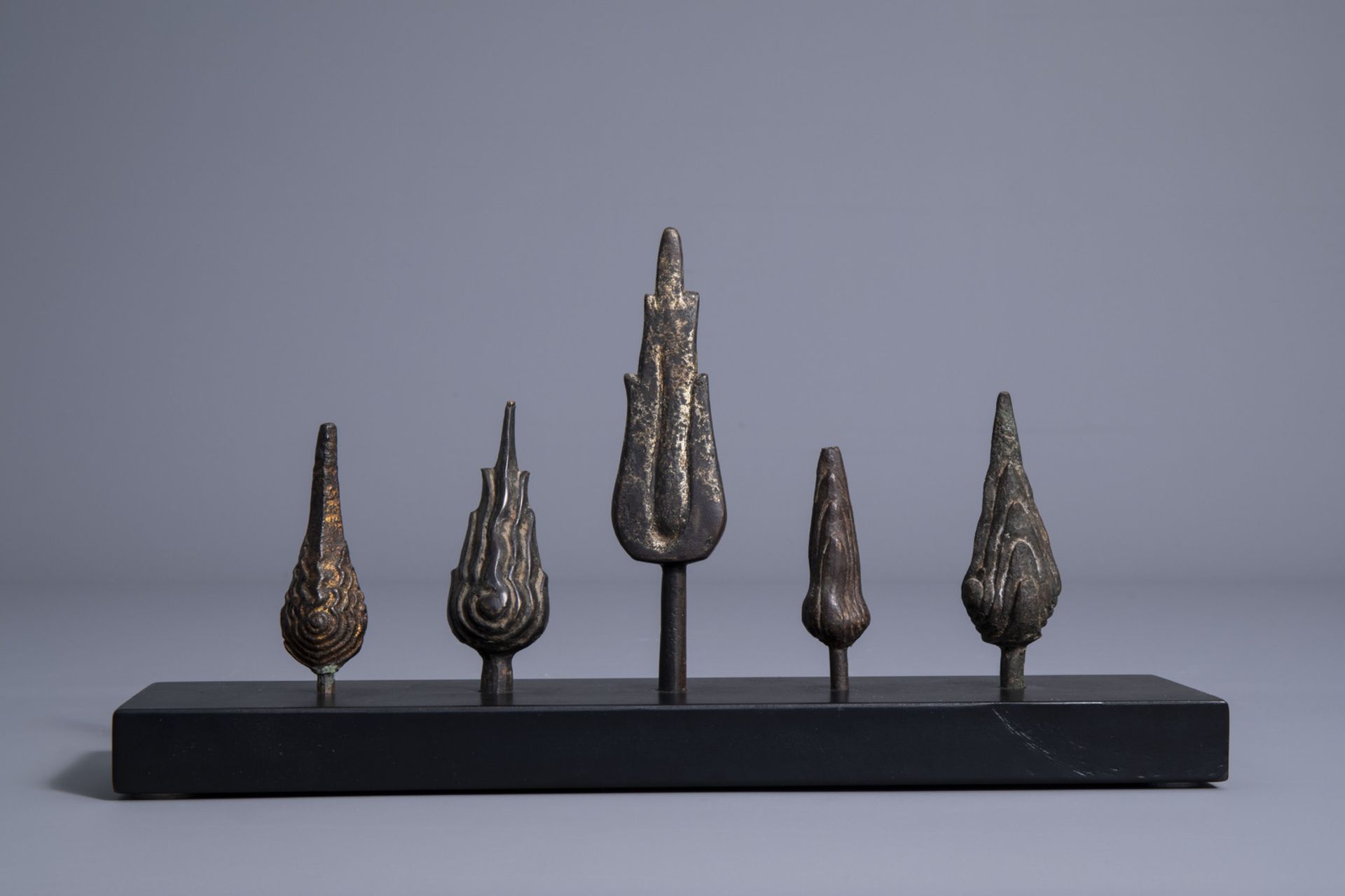 Five patinated and gilt bronze ushnishas on a wooden stand, Thailand/Cambodia, 19th/20th C. - Image 4 of 7