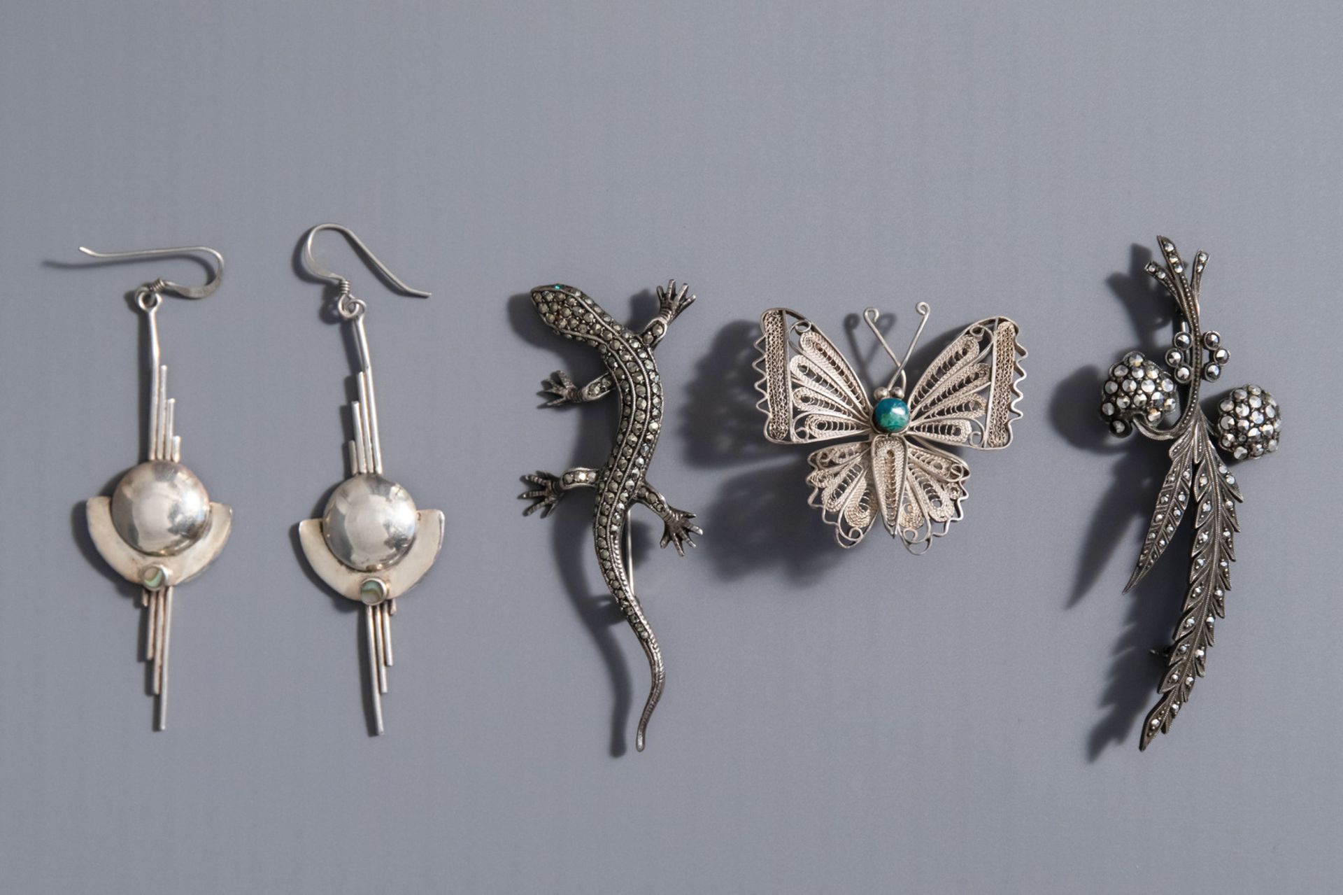 A varied collection of silver jewelery consisting of three brooches and a pair of earrings, 20th C.