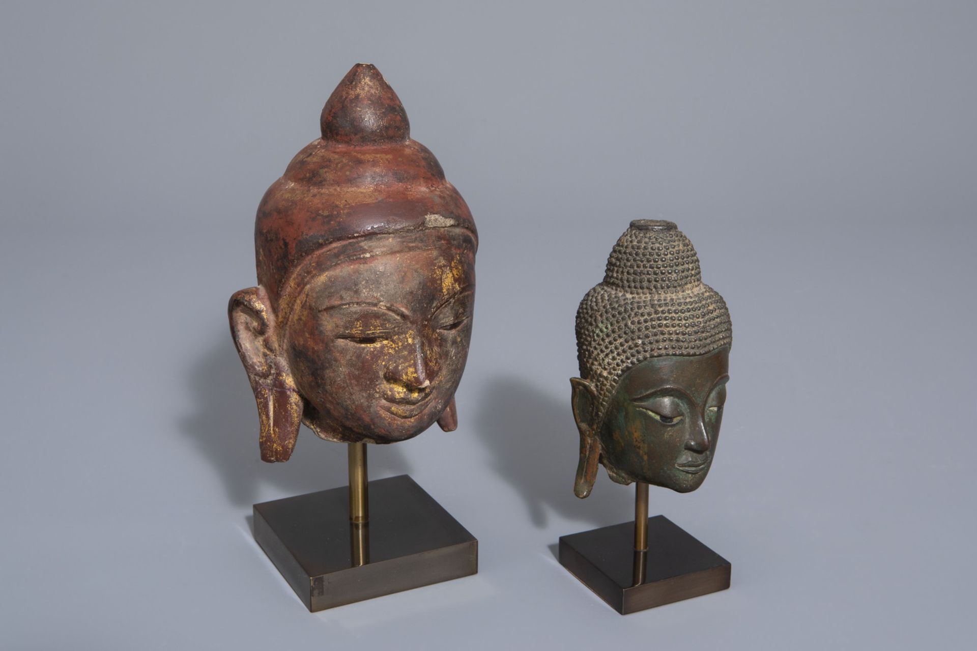 Two patinated bronze and gilt and polychrome painted stone Buddha heads, Burma/Thailand, 19th/20th C