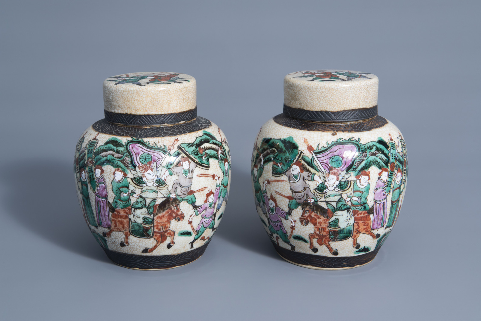 A pair of Chinese Nanking crackle glazed famille rose jars and covers with warrior scenes, 19th C.