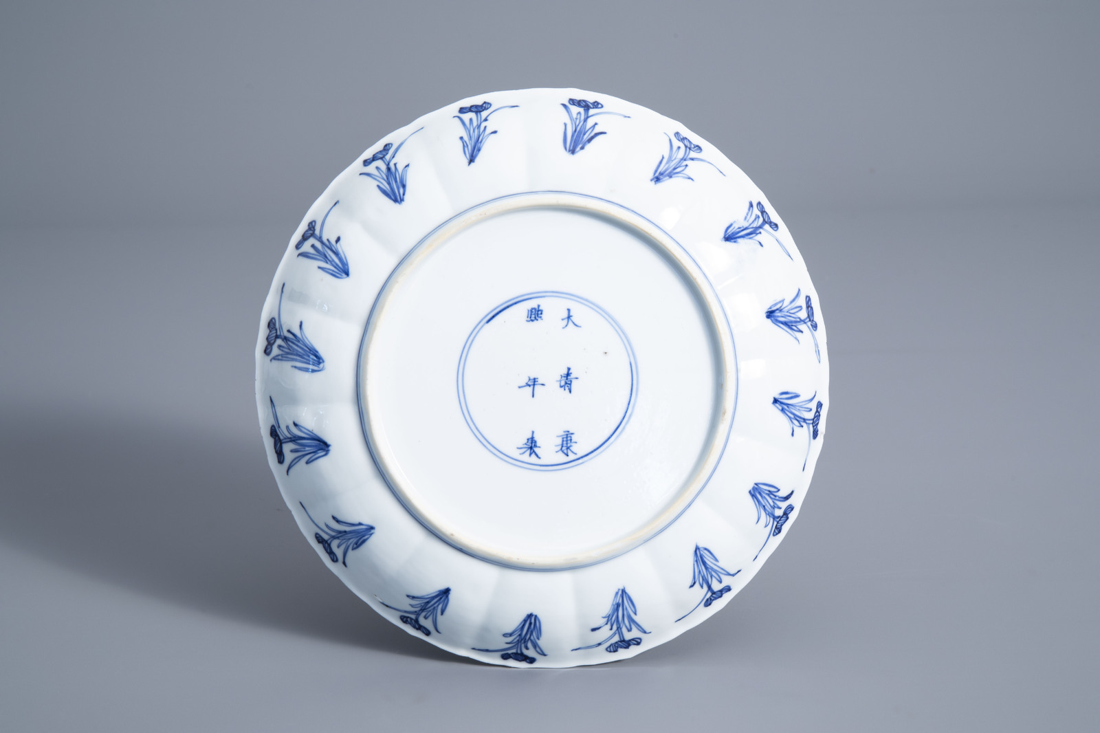 A Chinese blue and white plate with a tea ceremony and floral design, Kangxi mark and of the period - Image 2 of 2