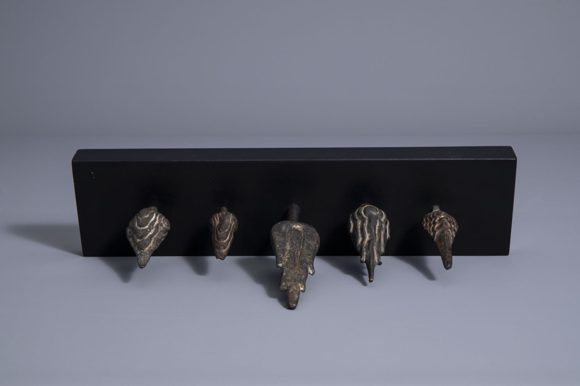 Five patinated and gilt bronze ushnishas on a wooden stand, Thailand/Cambodia, 19th/20th C. - Image 7 of 7