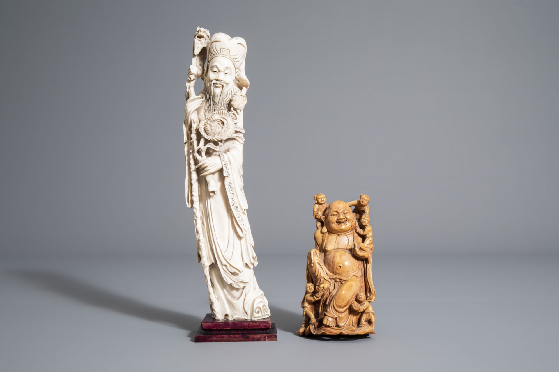 Two Chinese carved figures of an Immortal and a Buddha with children, 19th/20th C.