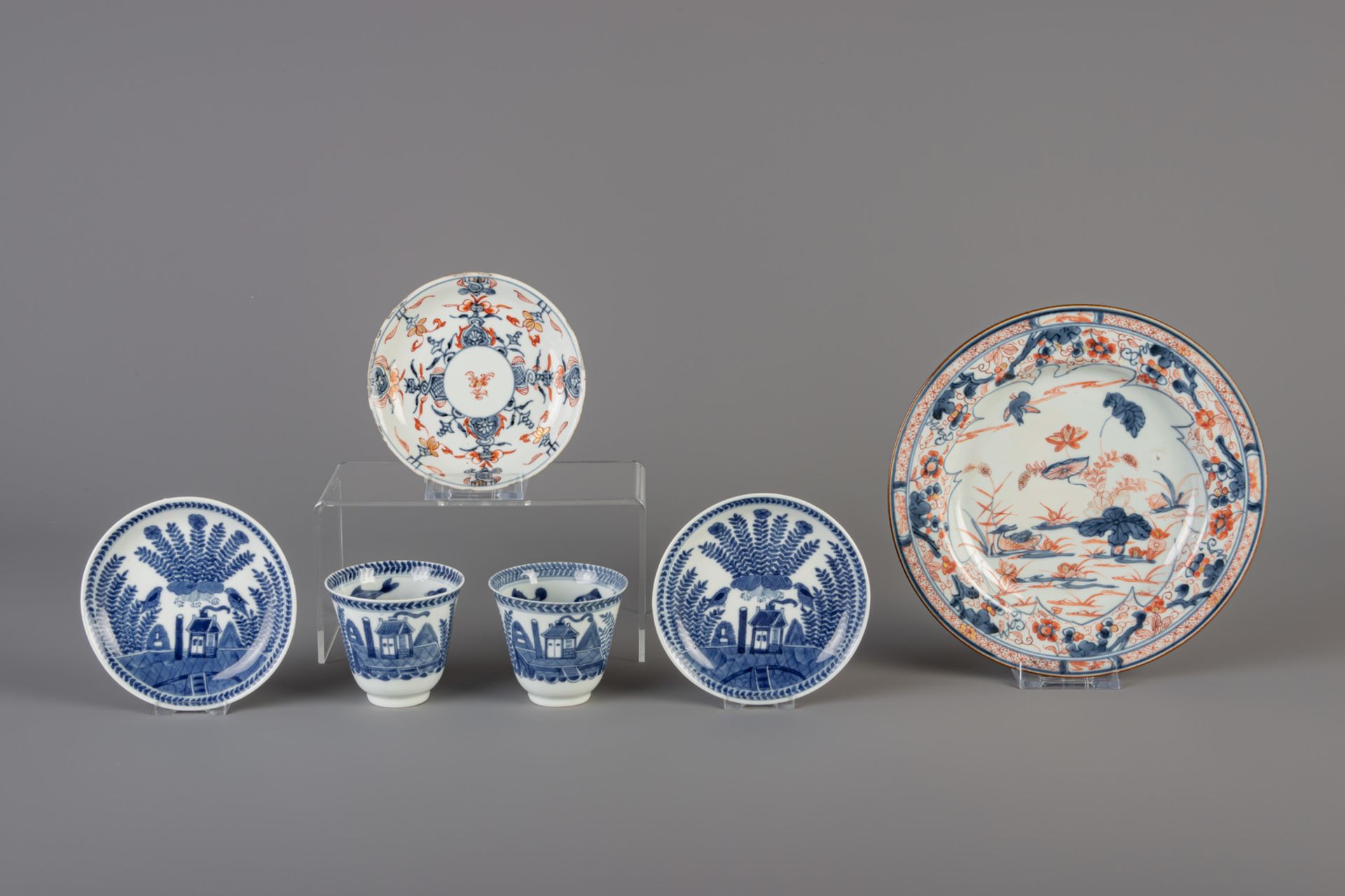 A pair of Chinese blue and white cups and saucers and two Imari style plates, 18th/19th C.
