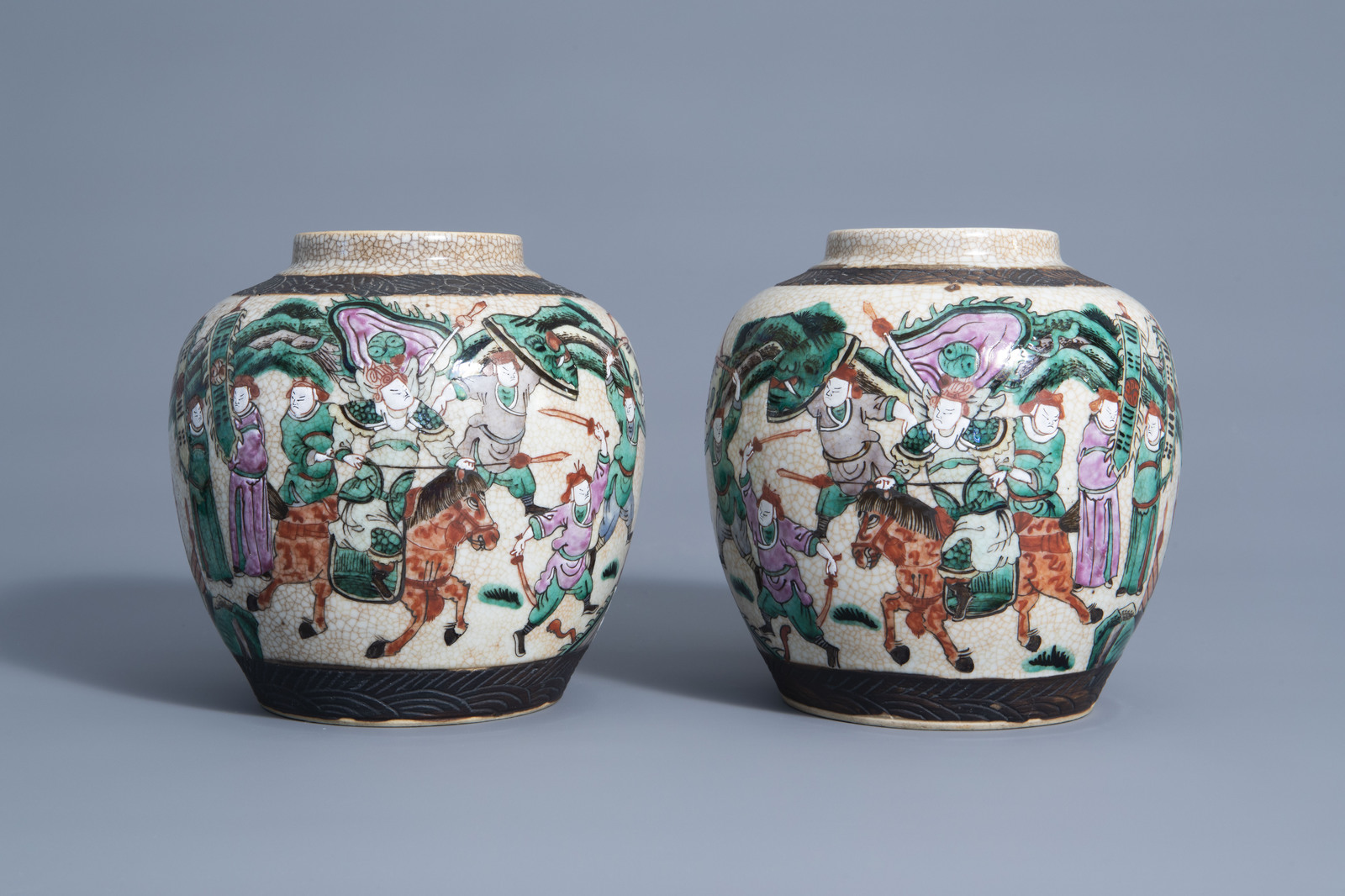 A pair of Chinese Nanking crackle glazed famille rose jars and covers with warrior scenes, 19th C. - Image 2 of 7