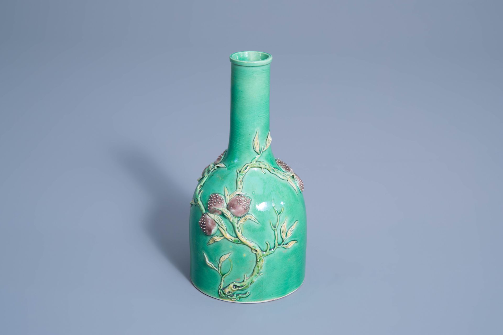 A Chinese verte biscuit vase with relief design of nine peaches, 19th/20th C.