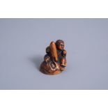 A Japanese wooden netsuke of a child on a mask, signed Masakatsu, Meiji, 19th/20th C.