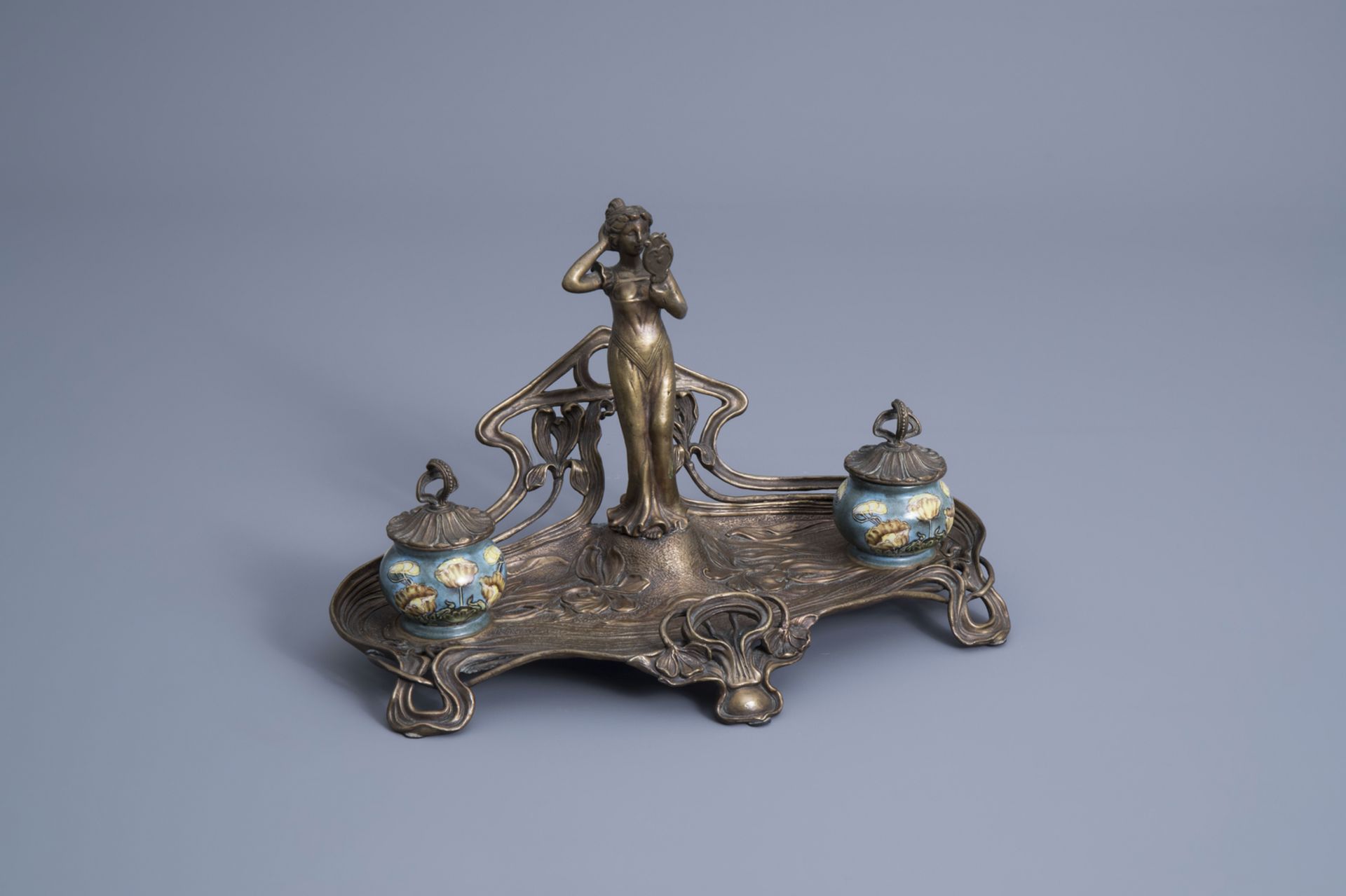 A brass Art Nouveau style ink well with floral design and a lady looking in the mirror, 20th C.