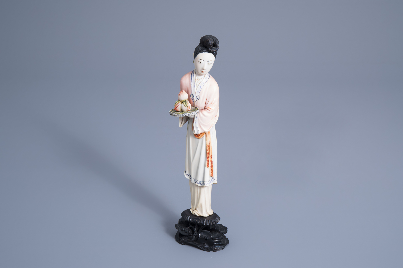 A Chinese polychrome ivory figure of a lady holding a tray of peaches, first half 20th C.