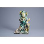 A Chinese sancai glazed figure of a guardian with a monkey, Ming