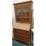 Pine bureau bookcase with ogee moulded pediment above two glazed doors enclosing shelves and a