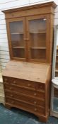 Pine bureau bookcase with ogee moulded pediment above two glazed doors enclosing shelves and a