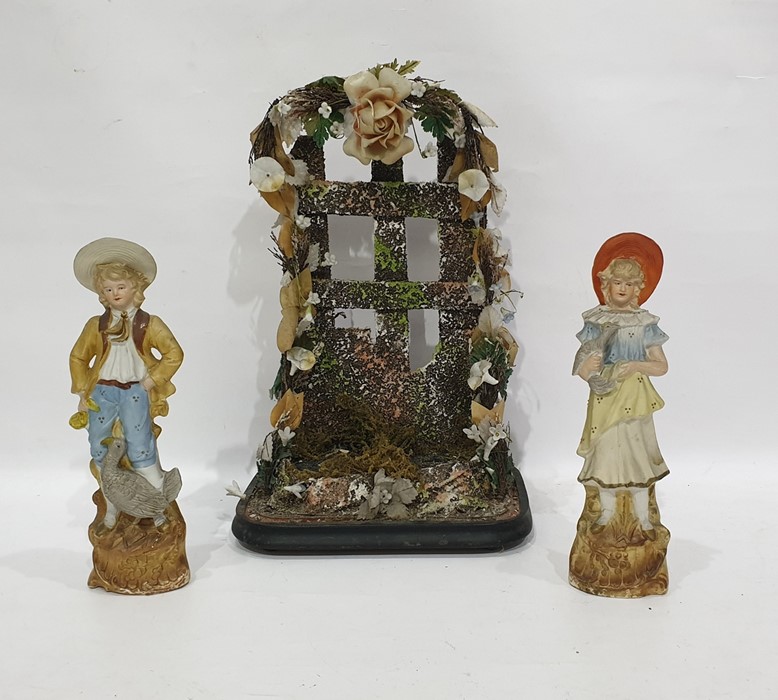Pair late 19th century tinted bisque figures of boy and girl with birds and a floral applied