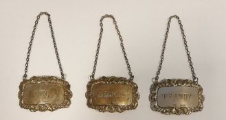 Set of three silver wine labels "Brandy", "Sherry" and "Gin" with rococo scallopshell borders,