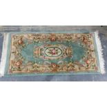 Two small Chinese washed wool rugs, one oval shape with olive green and cream pattern decorated with