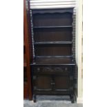 Dark oak dresser with open shelves above single drawer, two cupboard doors, turned and block feet