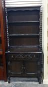 Dark oak dresser with open shelves above single drawer, two cupboard doors, turned and block feet