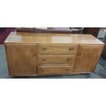 Light elm Ercol sideboard with three central drawers flanked by cupboard doors, the whole raised