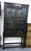 20th century oak display cabinet with leaded glazed Art Nouveau doors enclosing shelves, raised upon