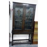 20th century oak display cabinet with leaded glazed Art Nouveau doors enclosing shelves, raised upon