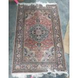 Persian style rug with salmon field, with palmette arabesque and spandrels surrounded by floral