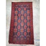 Eastern blue ground rug with repeating pattern, in reds, creams, oranges three-margin border,