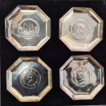 Set of four octagonal Eastern silver ashtrays, each inset with coin, the mount stamped 'Sterling',