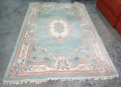 Chinese green ground rug with central cream ground motif, 273cm x 181cm