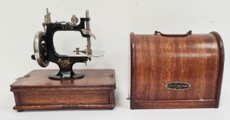 Child's miniature hand-held sewing machine, in oak case