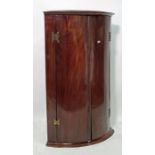 19th century mahogany bowfront wall-hanging corner display cabinet, the two doors opening to
