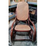 After design by Thonet, a bentwood rocking chair with cane back and seat