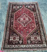 Persian rug, the central medallion with hooked motif, red ground field with flowerhead decoration,