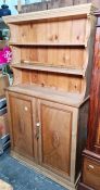 Probably early 20th century pine dresser with open shelves above two cupboard doors, plinth base,