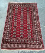 Persian rug, red ground field bearing three rows of 14 guls, on a stepped border with repeating