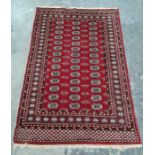 Persian rug, red ground field bearing three rows of 14 guls, on a stepped border with repeating