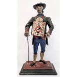 A painted metal travelling figure with painted clock to his front, Roman numeral dial with painted