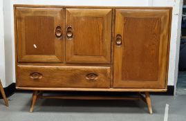 Light elm Ercol sideboard with three cupboard doors and single drawer, raised on turned beech