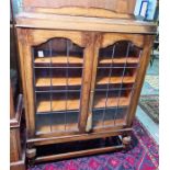 20th century oak display cabinet with two leaded glazed doors enclosing shelves, raised on turned