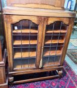 20th century oak display cabinet with two leaded glazed doors enclosing shelves, raised on turned