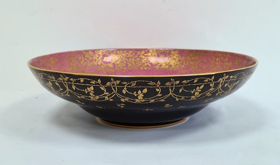 Royal Worcester porcelain shallow bowl, matt black glazed with gilt foliate border to exterior,