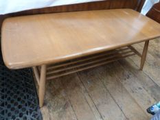 Ercol elm coffee table, rounded rectangular with rail under shelf, on turned tapering supports,