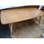 Ercol elm coffee table, rounded rectangular with rail under shelf, on turned tapering supports,